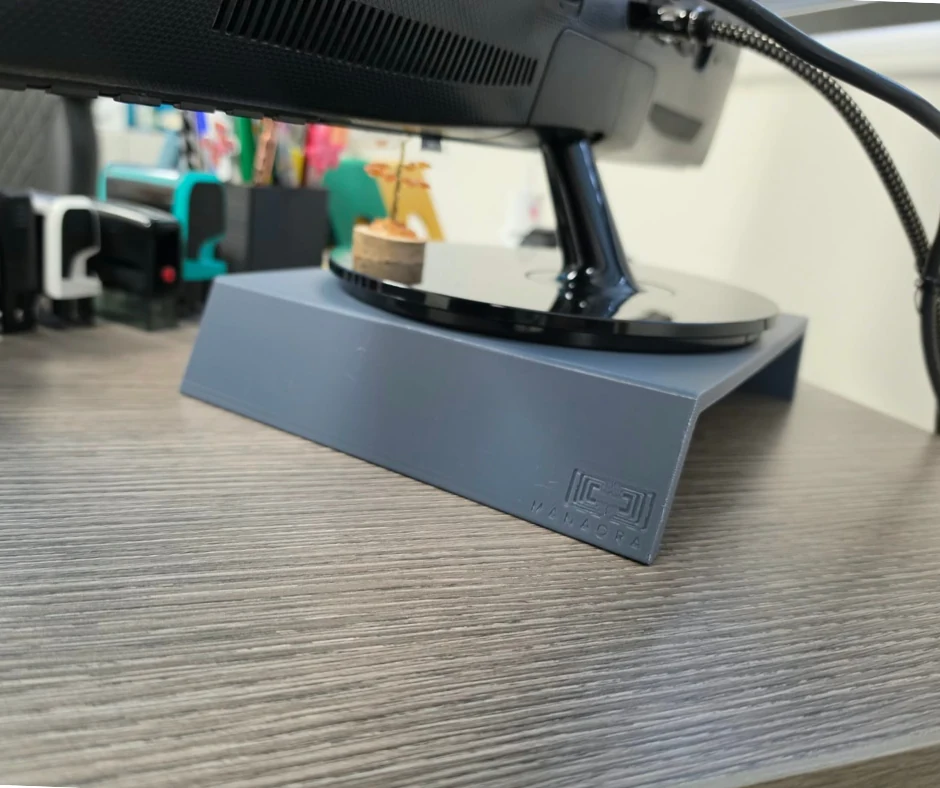 Support d'écran de bureau Manaora en gris ardoise, logo Manaora gravé, placé sous un écran — imprimé en 3D à Tahiti